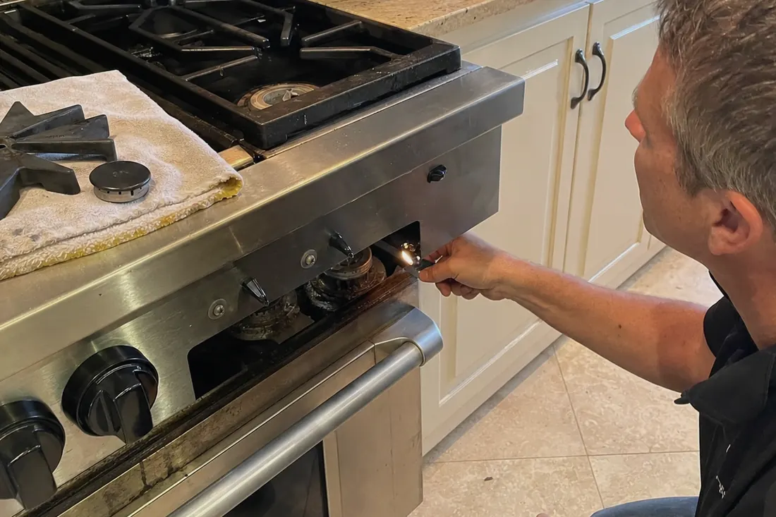 Technician checking the igniter on a dual-fuel range, one burner cap lifted off - Salt Air and Your Outdoor Kitchen Appliances