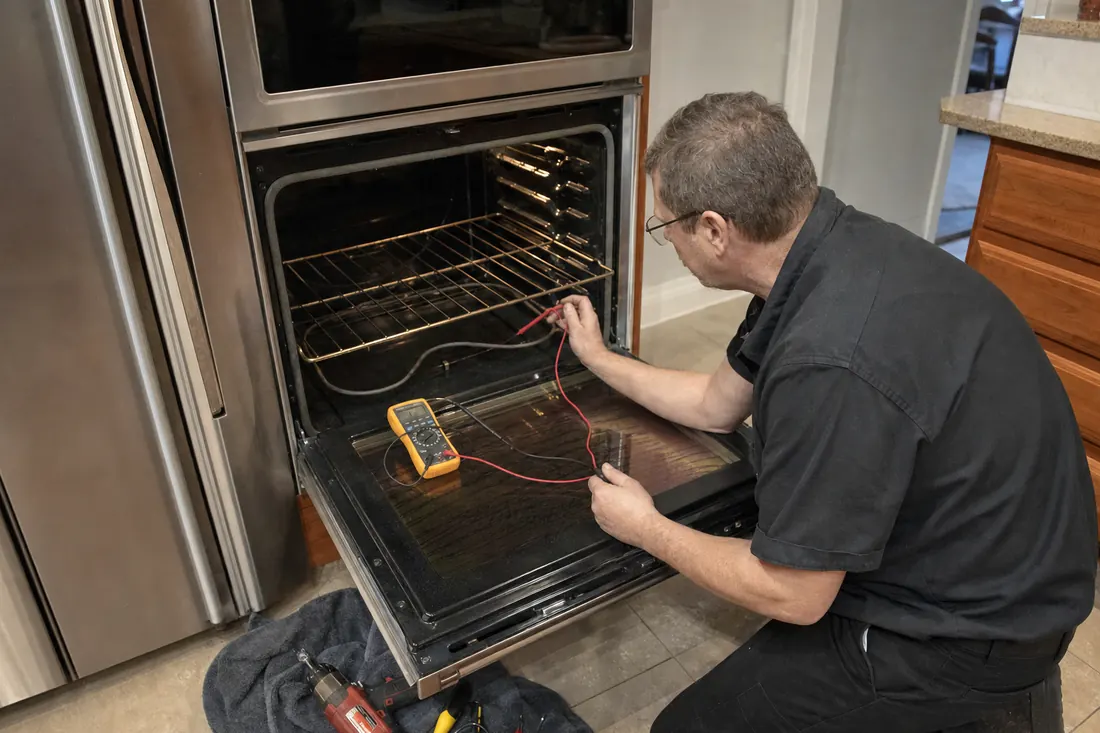 Technician testing the bake element of an open double wall oven with a multimeter, the multimeter leads in frame - Monogram repair in Jacksonville and Northeast Florida