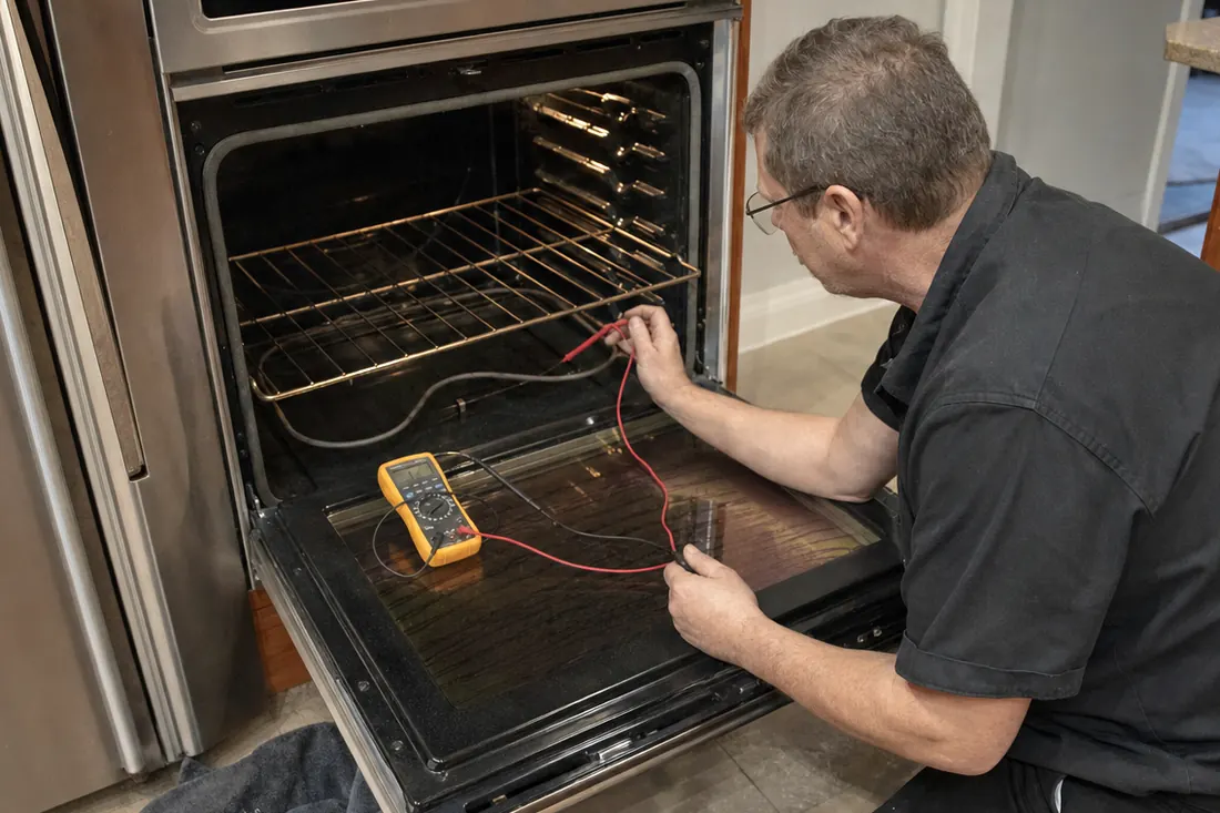 Technician testing the bake element of an open double wall oven with a multimeter, the multimeter leads in frame - Sub-Zero and luxury appliance repair in Ortega